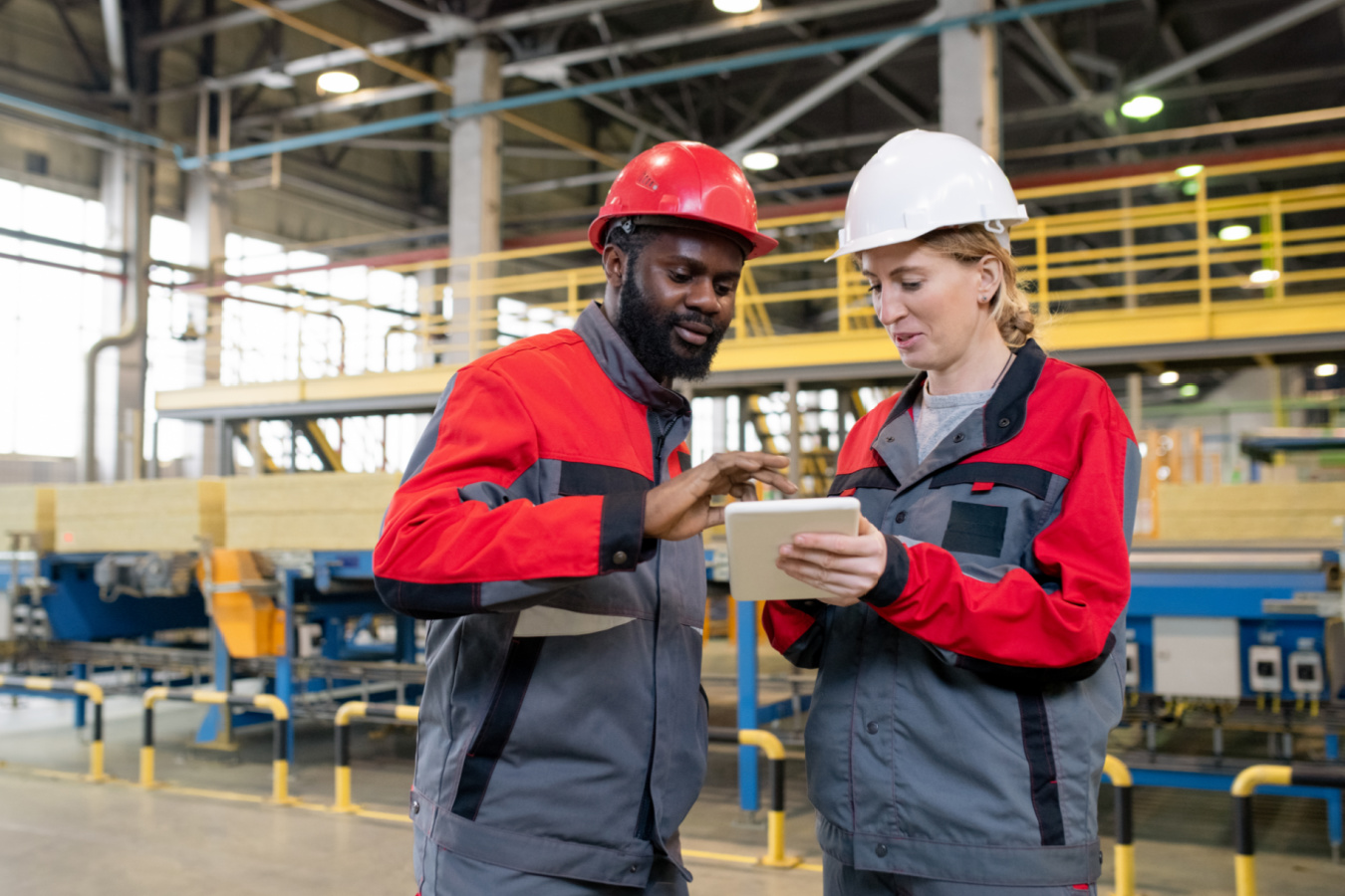 two workers wearing hard hats looking at tablet